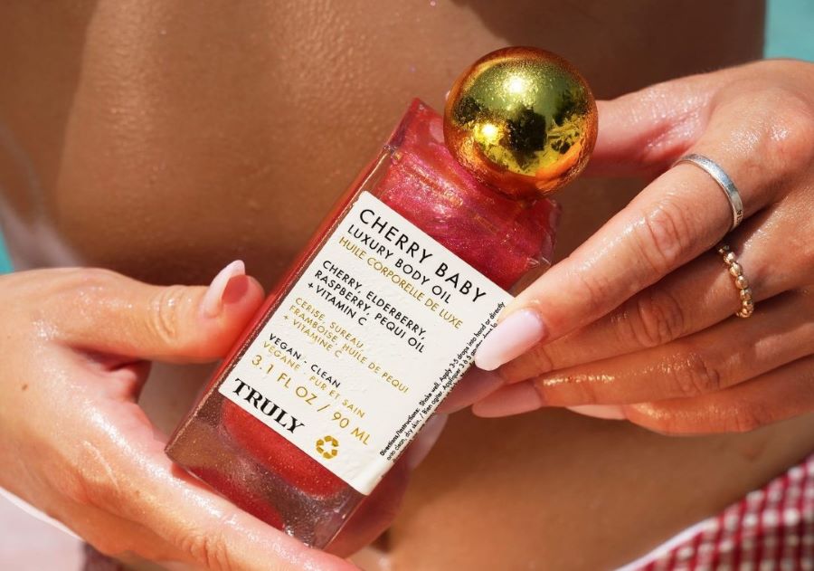 elderberry benefits for skin | closeup of truly beauty's cherry baby body oil held in front of woman's stomach