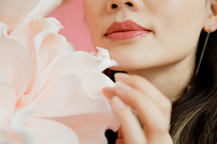 how to get rid of chapped lips | a woman wearing lipstick and playing with flowers