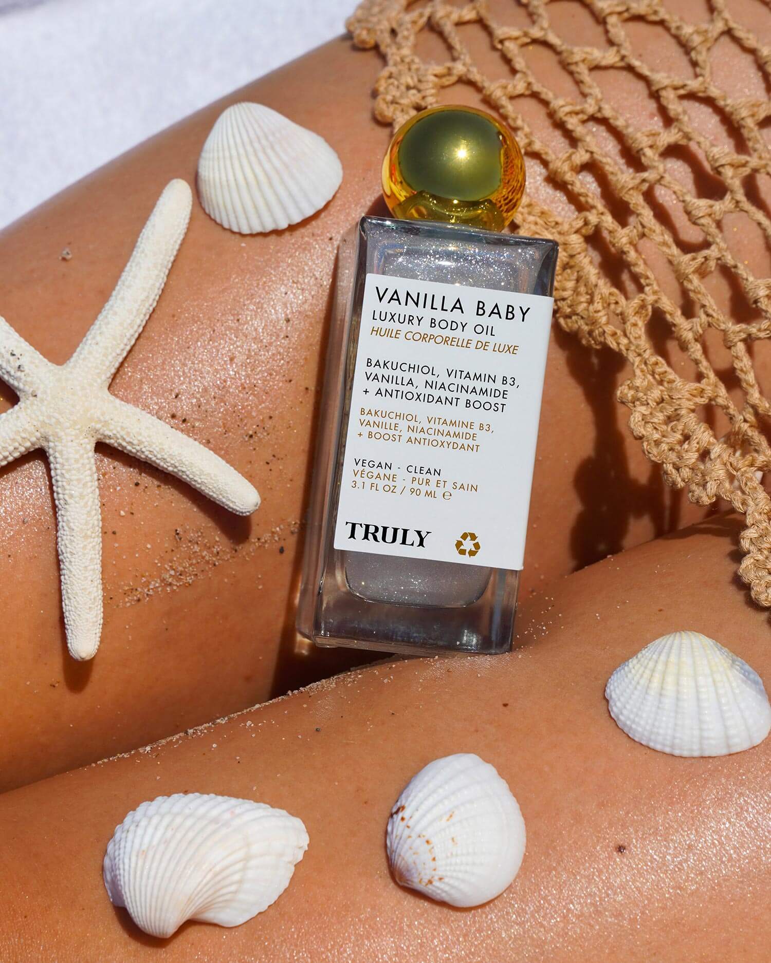 Kaylas Everyday Routine by Truly Beauty sits on glowing skin with a fishnet cover, white seashells, and a starfish beside Soft Serve Whipped Shave Butter, creating a fresh, beachy summer vibe.
