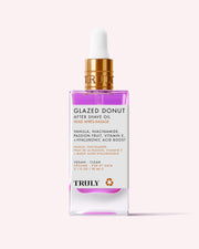 A pink and clear glass dropper bottle labeled Glazed Donut After Shave Oil, highlighting skin-smoothing niacinamide, vitamin E, and hyaluronic acid, is shown on a light pink background.