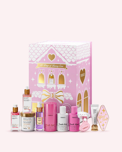 A pink and white 10 Days of Luxury Advent Calendar by Truly Beauty is surrounded by gold and pink-accented skincare jars, bottles, tubes, and a heart-shaped item.