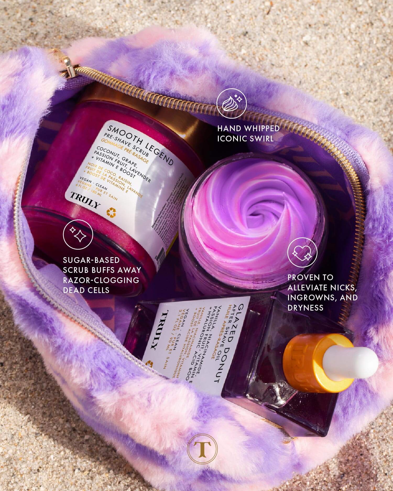 A fluffy purple and pink pouch on sand holds the Ultimate Smooth Legend Shave Set by Truly Beauty: a purple swirl cream, sugar scrub, and shaving serum with yellow dropper—highlighting exfoliation and dryness relief benefits.
