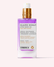 A rectangular bottle of Glazed Donut After Shave Oil with a gold pump and white label stands against a pale pink background. The light purple oil inside helps smooth and soften skin after shaving.