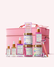 The Smooth Legend Complete Collection by Truly Beauty, featuring serums, creams, and a luxury shave kit with colorful labels and pastel packaging, arranged before a large pink cosmetic case.