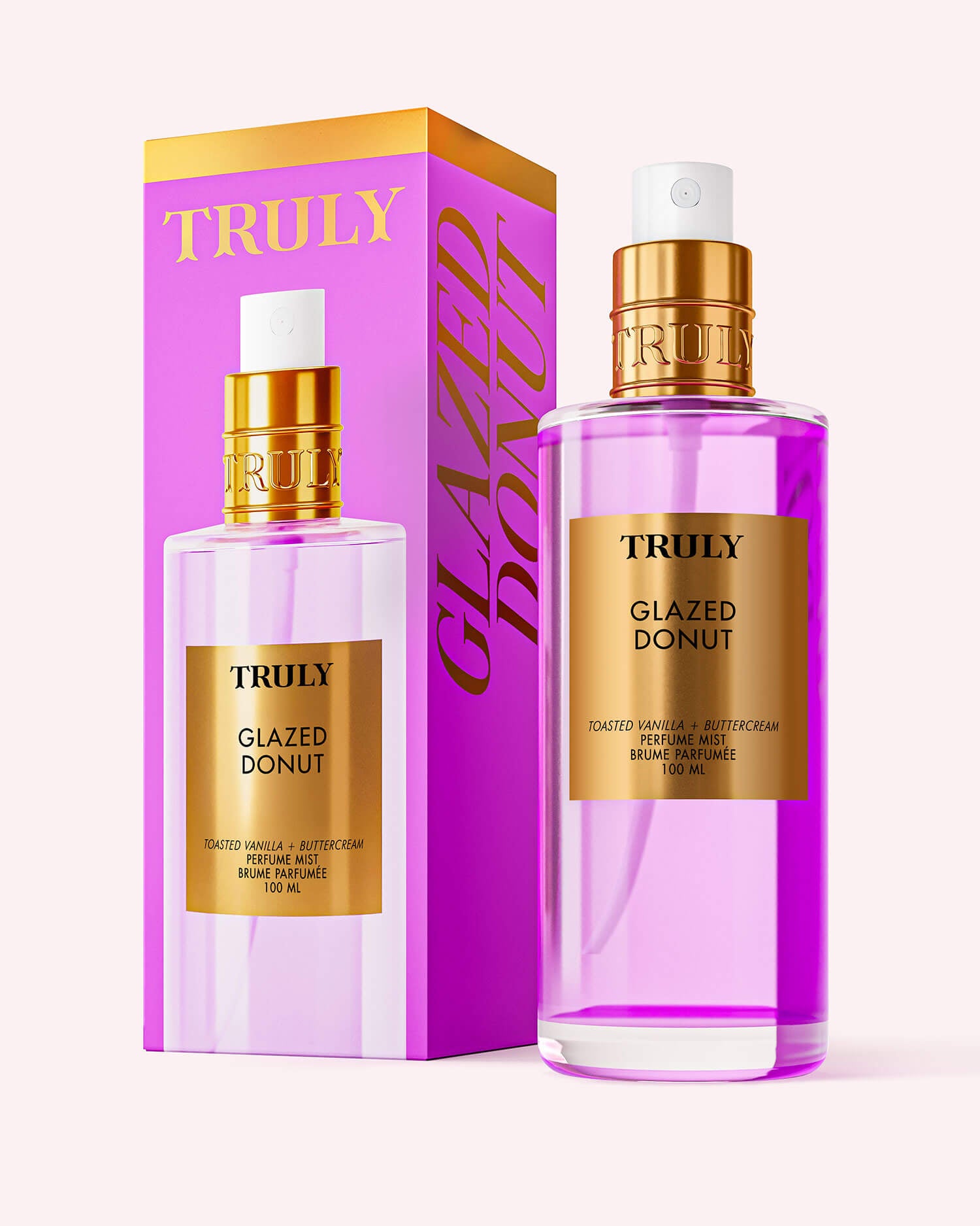 A pink and gold bottle of Truly Beauty Glazed Donut Perfume Mist stands beside its matching box, labeled “Toasted Vanilla + Buttercream Perfume Mist, 100 mL,” on a soft pink background.