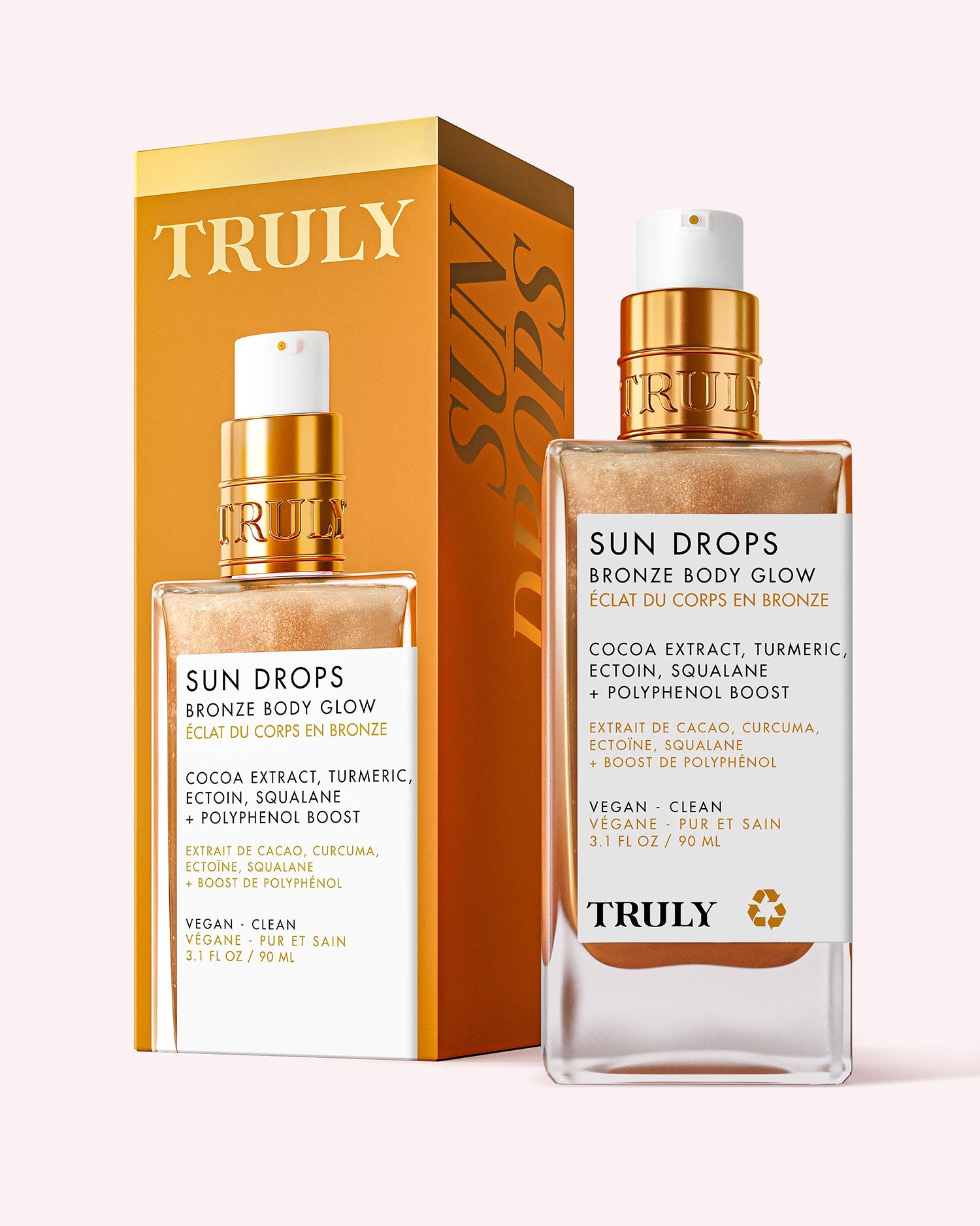 A bottle of Truly Beauty Sun Drops Bronze Body Glow with a spray nozzle stands before its matching yellow and gold box. The label features hydrating cocoa extract, turmeric, and squalane for a sunkissed glow.