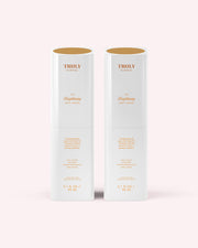 Two white cylindrical bottles of Truly Beauty The Brightening Body Serum (3.1 fl oz each) with gold text stand side by side on a light pink background. This serum targets hyperpigmentation and reduces the appearance of dark spots.