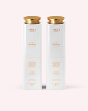 Two white bottles of Truly Beauty’s The Brightening Body Serum, 3.1 fl oz (90 mL) each with gold caps, stand side by side on a light pink background—ideal for targeting dark spots and hyperpigmentation.