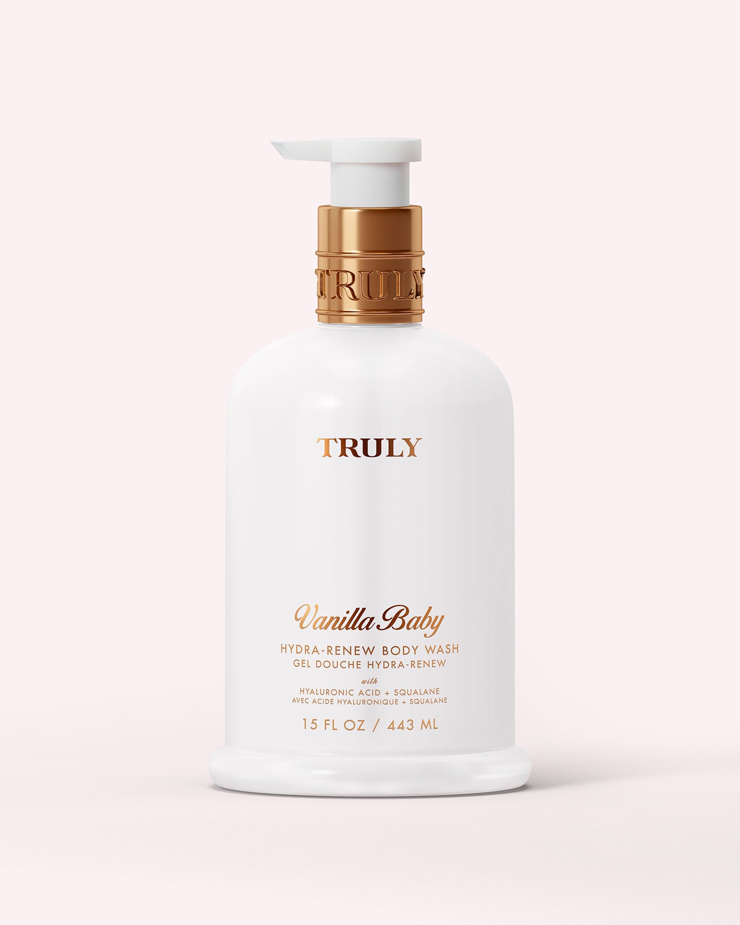 A white 15 fl oz bottle of Truly Beauty Hydra-Renew Body Wash with a gold pump and label sits on a pale pink background. This sulfate-free wash gently cleanses and nourishes delicate skin.