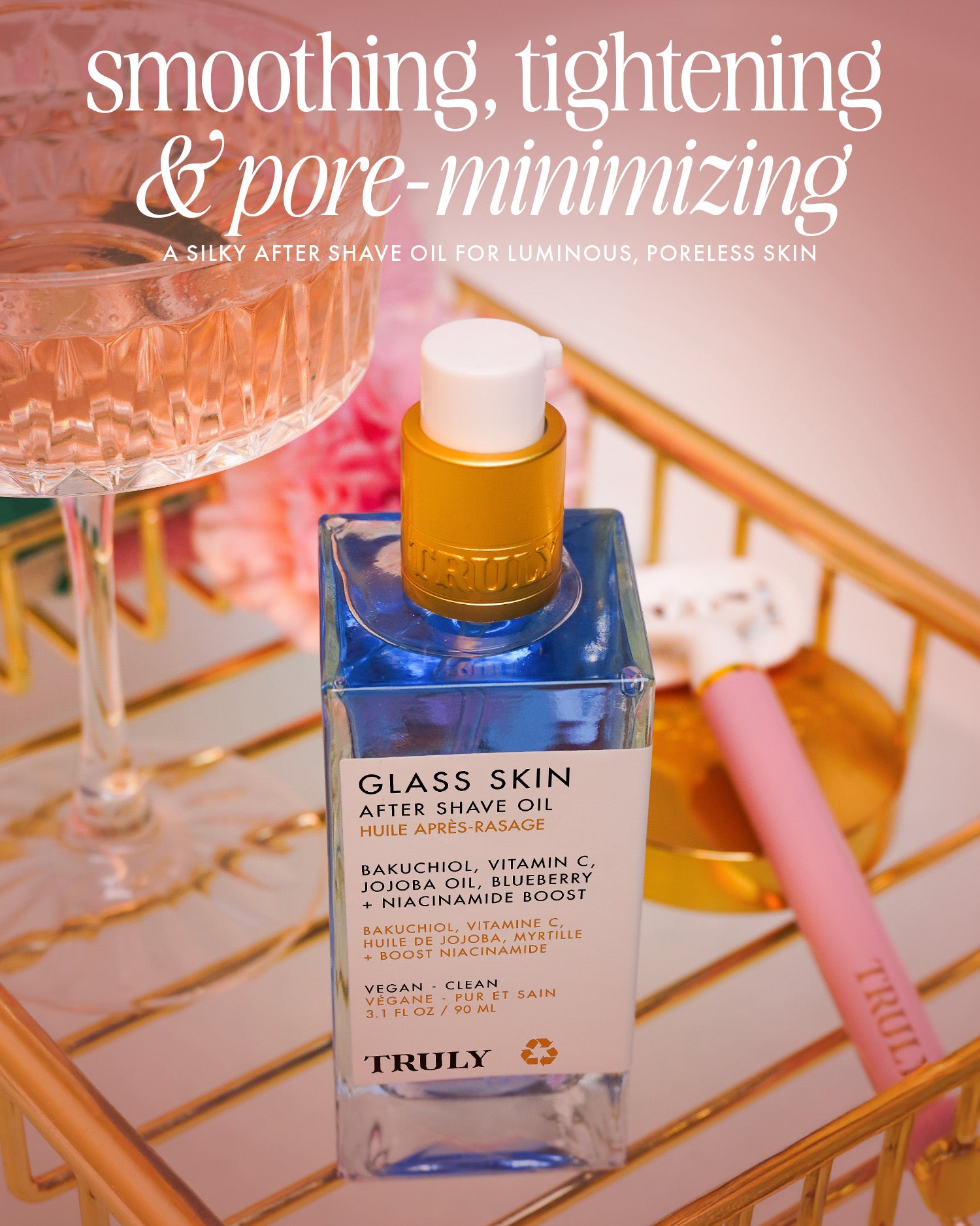 A bottle of Truly Beauty Glass Skin After Shave Oil rests on a gold tray with cotton swabs and a pink beauty tool, showcasing its smoothing, tightening, and pore-minimizing effects for a glass skin finish.