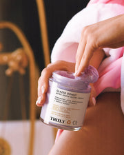 A person holding Truly Beauty’s Glazed Donut After Shave Glow Cream, ideal as a body moisturizer or for achieving a radiant, luminous glow after shaving.