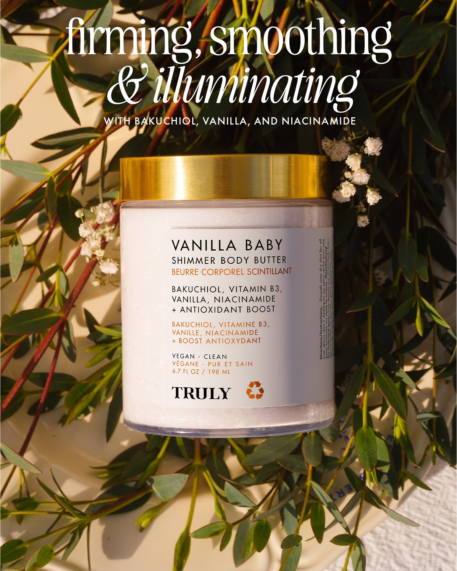 A Vanilla Baby Luxury Trio by Truly Beauty rests on a surface with small white flowers. The label showcases bakuchiol, vanilla, niacinamide, and vitamin B3 for luminous skin. Text above says: firming, smoothing & illuminating.