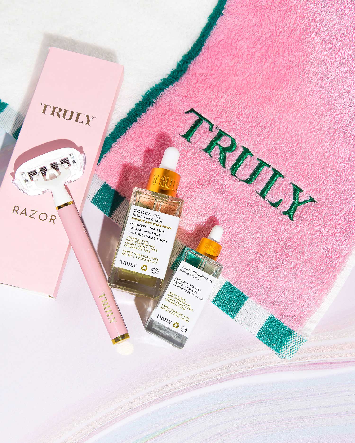 The Smooth Legend - Complete Collection by Truly Beauty features a pink razor, two skincare serums, and a pink TRULY-embroidered towel—the perfect shave kit for your Smooth Legend routine. Razor box and bottles display the Truly Beauty brand.