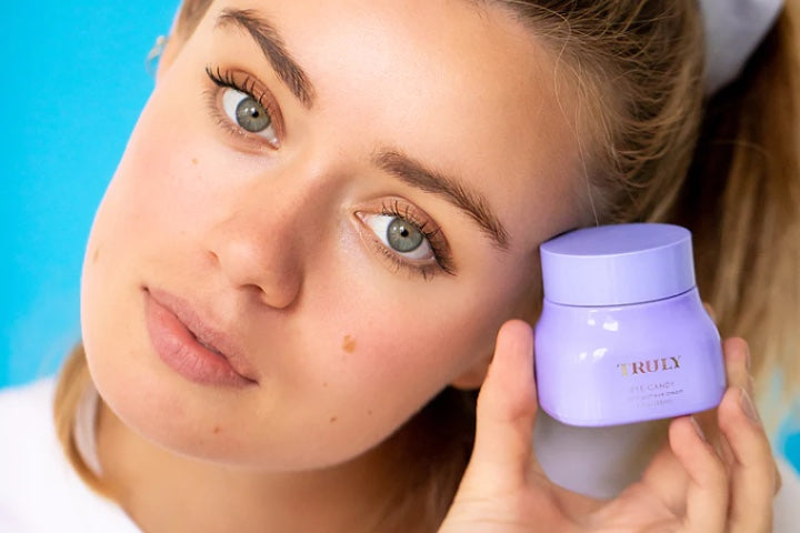 young woman holding Truly face cream beside face