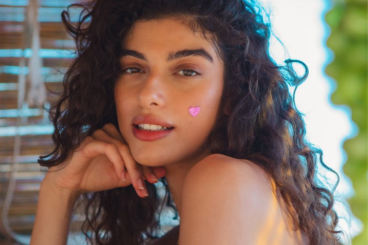 closeup of young brown-haired woman with heart pimple patch on cheek
