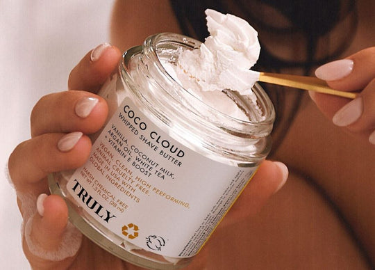young woman with wet hair holding Truly's shampoo and conditioner