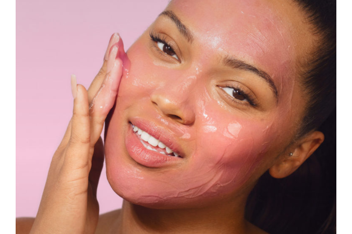 Closeup of young woman applying pink gel face mask to face