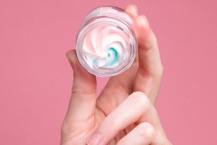 closeup of hand holding tiny jar with pink swirl