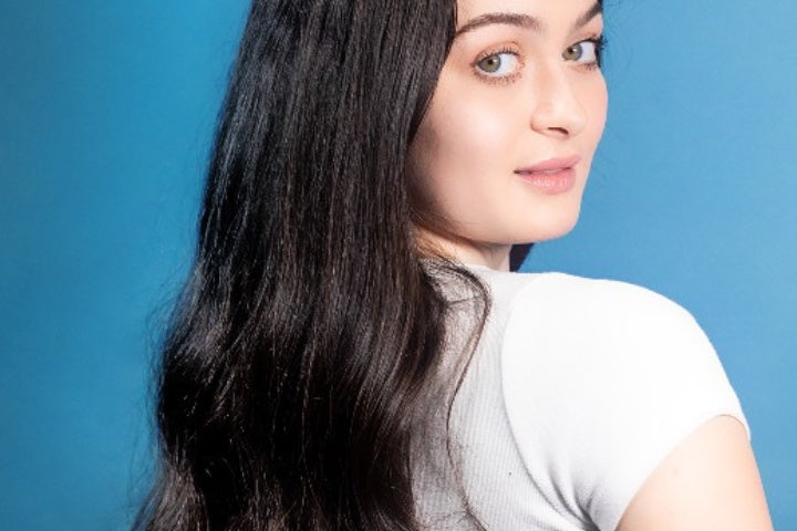 Young woman with long dark hair looking over shoulder
