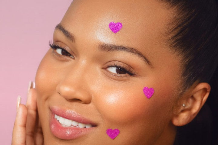 closeup of woman's face with three heart pimple patches