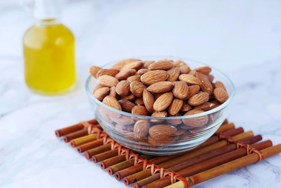 A glass bowl of almonds sits on marble table