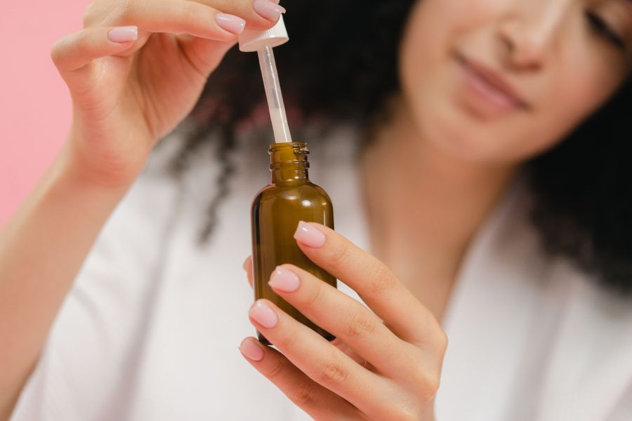 Mandelic acid for skin | Close-up of a woman using a dropper serum bottle.