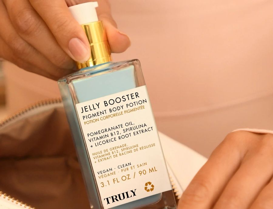 Gentle Hydroquinone Alternatives | close up of a woman holding a bottle of truly's jelly booster pigment body potion