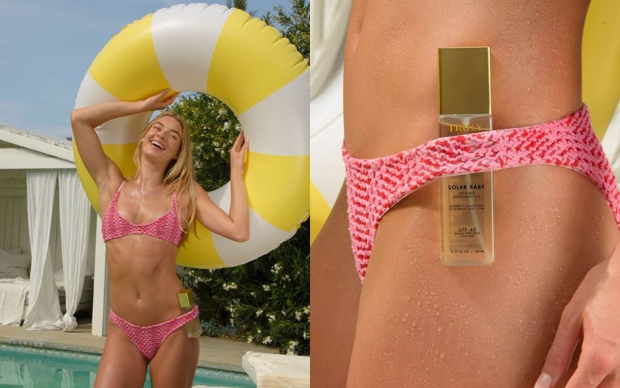Woman poolside with a yellow swim ring and Truly Solar Baby SPF 45 Invisible Sunscreen oil (brightening sunscreen) tucked into her pink bikini. Close-up view highlights the sunscreen's glow effect on wet, tanned skin.
