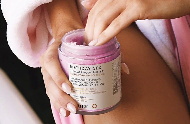 woman's hand in jar of Truly's birthday sex shimmer body butter
