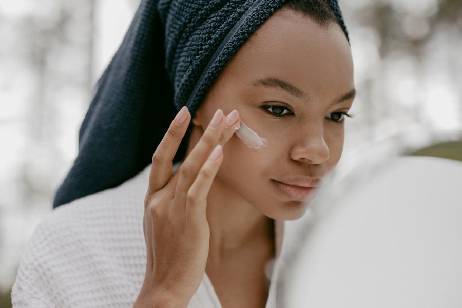 can sunscreen cause acne | woman in bathrobe applies face cream