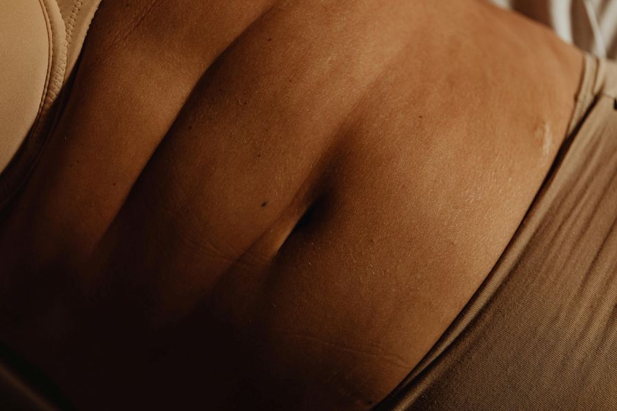 how to get rid of stomach cellulite | Detailed closeup of a woman's abdomen and bellybutton in beige underwear, showcasing skin texture