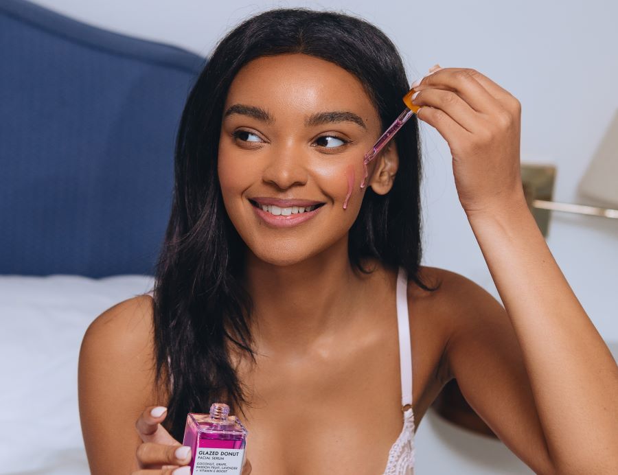 How to Make Your Skin Glow Naturally at Home | Black haired woman applying Glazed Donut serum to cheek