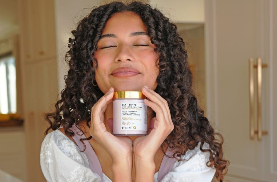 layer skincare products | Young woman with closed eyes holding Soft Serve After Shave Cream in front of her face