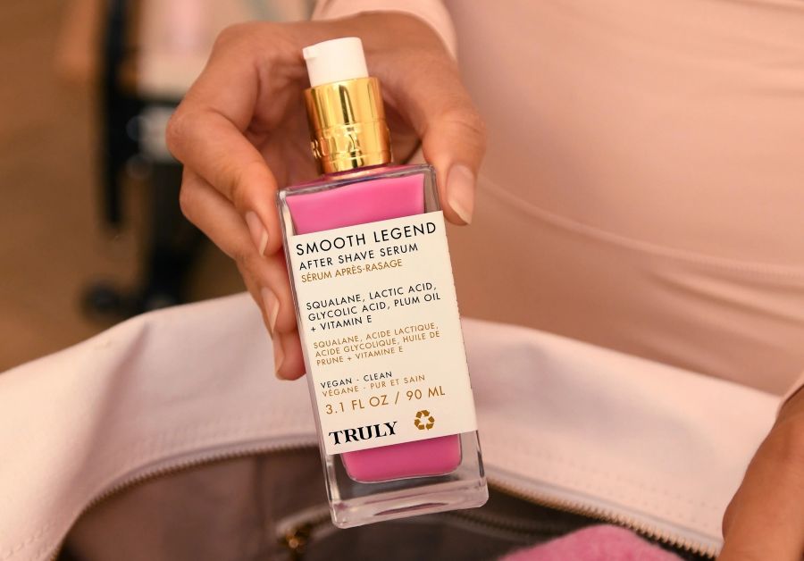 squalane benefits for skin | closeup of woman holding Truly's Smooth Legend Serum with Squalane over open bag