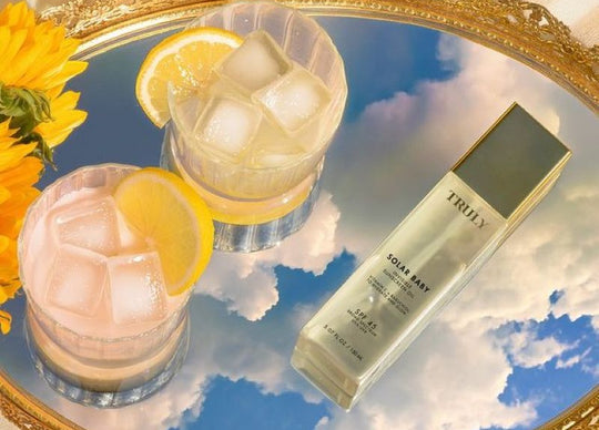 what is lip oil | side by side image - left image shows Truly's four new lip oils in bowl and right image shows woman with glossy lips holding vanilla baby lip oil