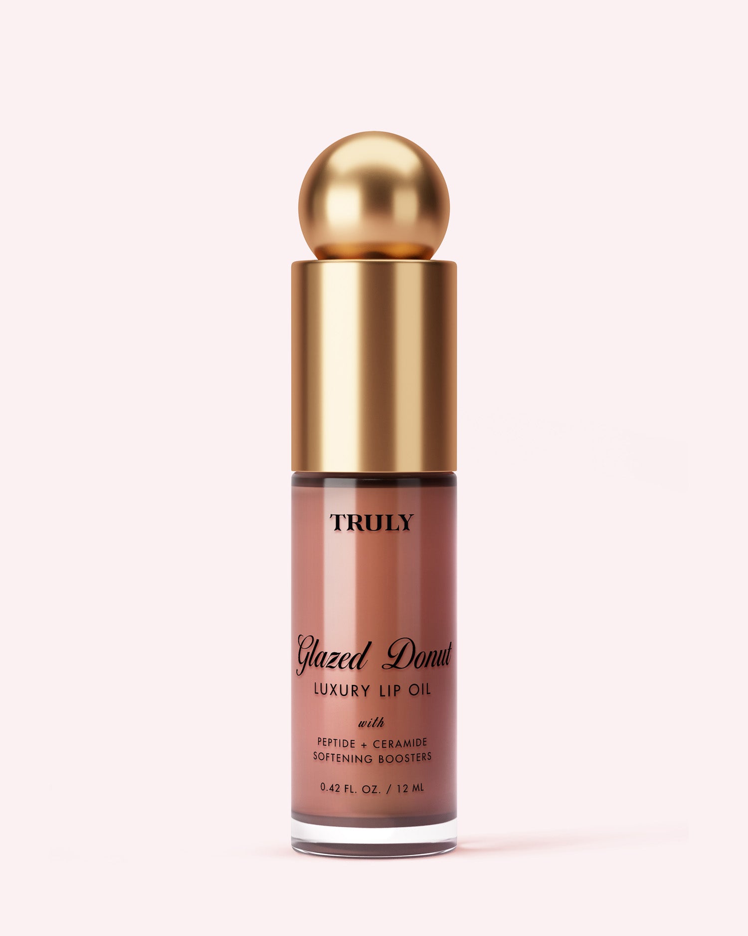 A bottle of Truly Beauty Luxury Peptide Lip Oil with a gold rounded cap, clear tube revealing pink-brown oil, and black and gold text on the label, set against a pale pink background.