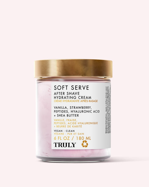 A glass jar of Truly Beauty Soft Serve After Shave Hydrating Cream with a gold lid. The label features vanilla, strawberry, peptides, hyaluronic acid & shea butter. This vegan, clean ingrown hair treatment comes in 6 fl oz/180 ml.