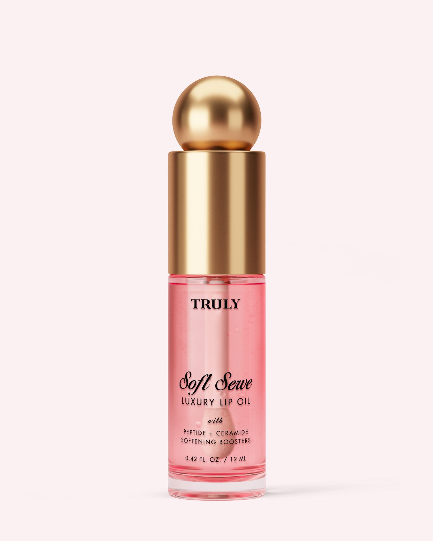 A clear pink bottle of Truly Beauty Luxury Peptide Lip Oil with a gold cap and round top, set against a light pink background. The label highlights peptides, ceramides, and softening boosters.