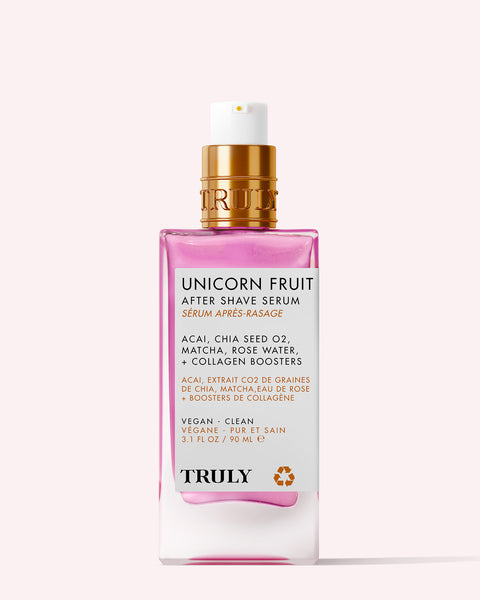 A pink and gold bottle of Truly Beauty’s Unicorn Fruit After Shave Serum with a pump dispenser, featuring acai, chia seed oil, matcha, and rose water—perfect for soothing skin and helping prevent ingrown hairs.