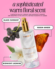 A bottle of Diamond Baby Treatment Body Serum by Truly Beauty is displayed with black currant berries, a white vanilla crème flower, and a white jasmine flower, highlighting its notes of black currant, vanilla crème, and midnight jasmine.