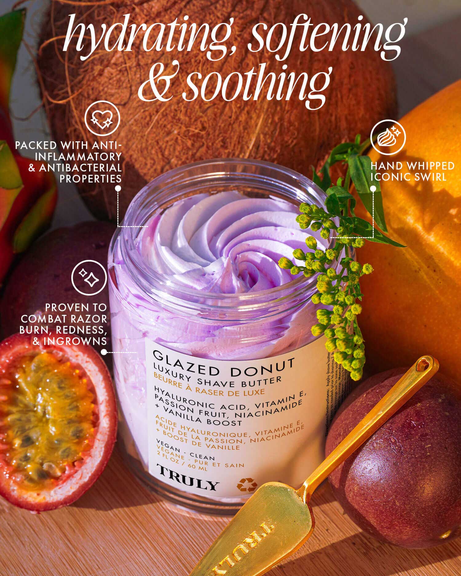 An open jar of Truly Beauty Glazed Donut Luxury Shave Butter with a purple swirl sits among coconuts and passionfruit, showcasing its hydrating, soothing, and anti-inflammatory formula. A gold spatula rests nearby.