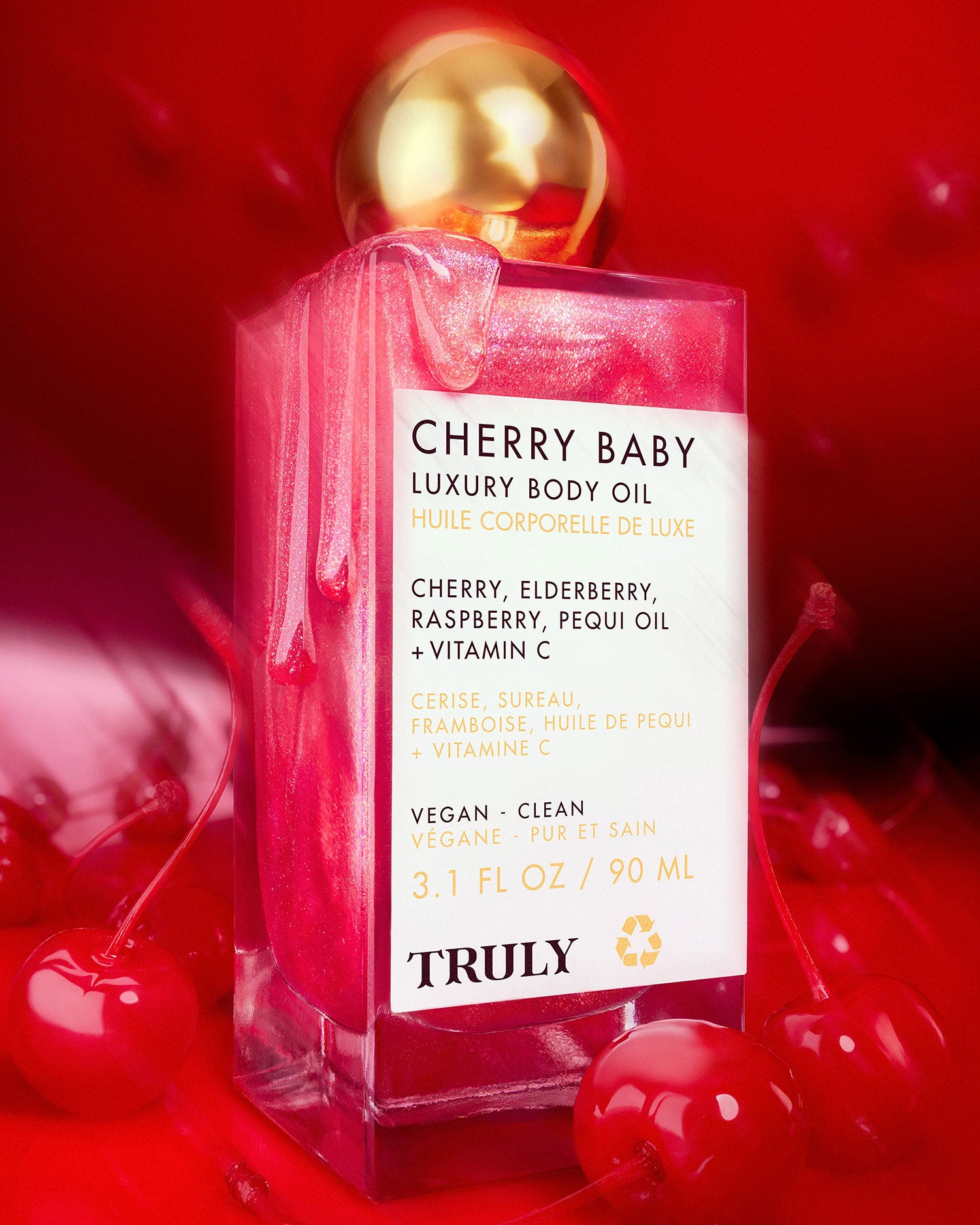 A pink bottle of Truly Beauty’s Cherry Baby Luxury Body Oil with a gold cap, featuring cherry, elderberry, raspberry, pequi oil, and vitamin C. This vegan formula delivers glowing hydration in every clean cherry-infused drop.