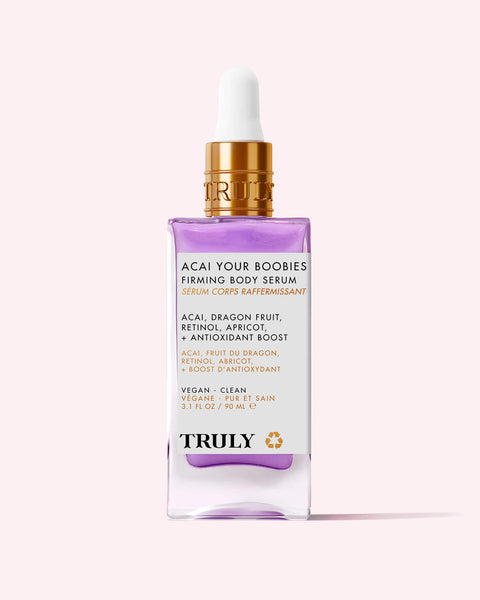 A bottle of Truly Beauty Acai Your Boobies Firming Body Serum with a gold dropper cap, highlighting its acai extract, retinol, apricot, and antioxidant-rich moisturizing formula on a light pink background.