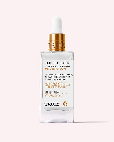 A clear glass dropper bottle of Coco Cloud After Shave Serum by Truly Beauty, with a gold and white dropper, featuring calming coconut, hydrating argan oil, vanilla, white tea, and vitamin E.