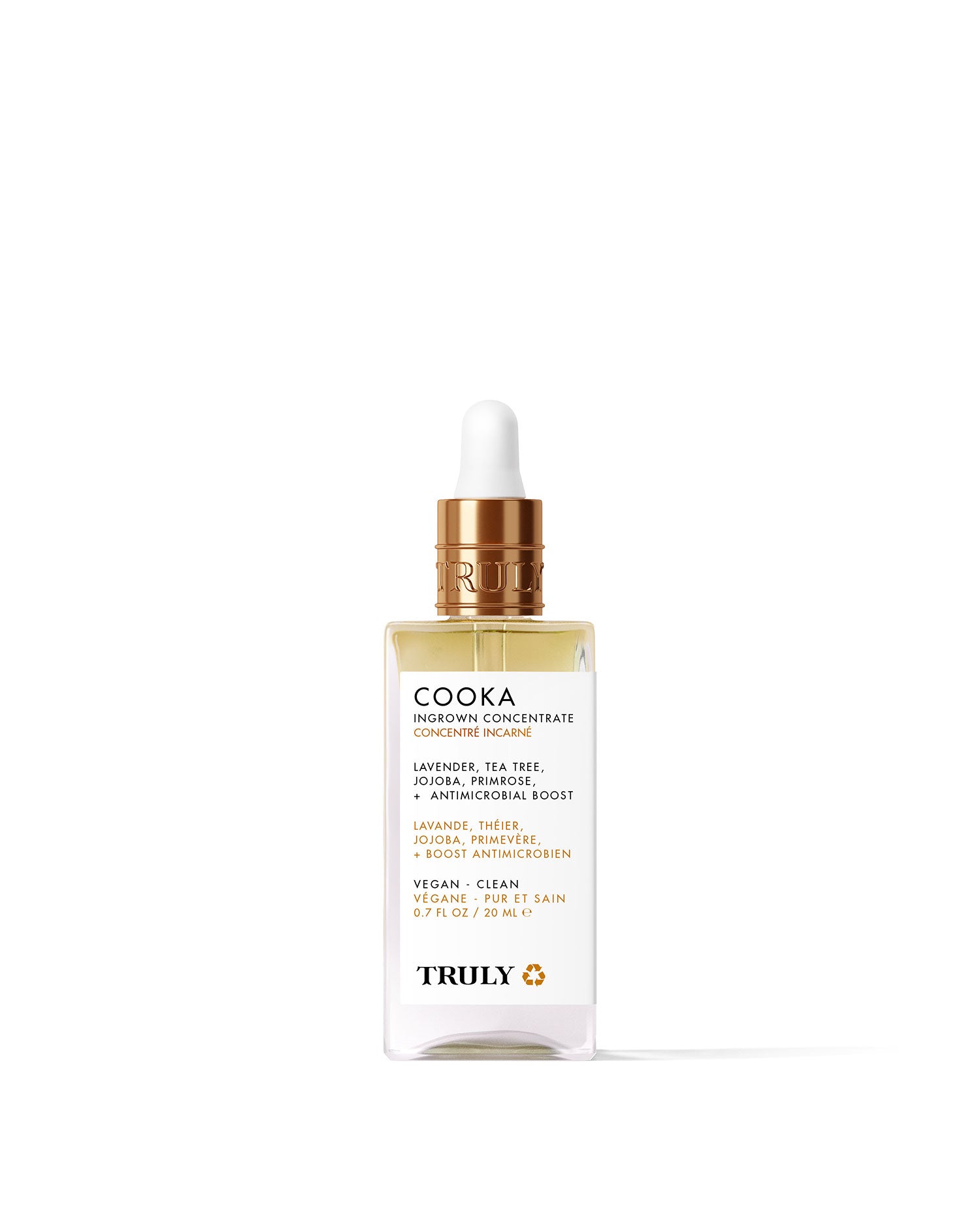 A glass dropper bottle of Truly Beauty’s Cooka Ingrown Concentrate with a gold cap, clear serum, and label listing lavender, tea tree, and jojoba for bikini line care—shown on a pale pink background.