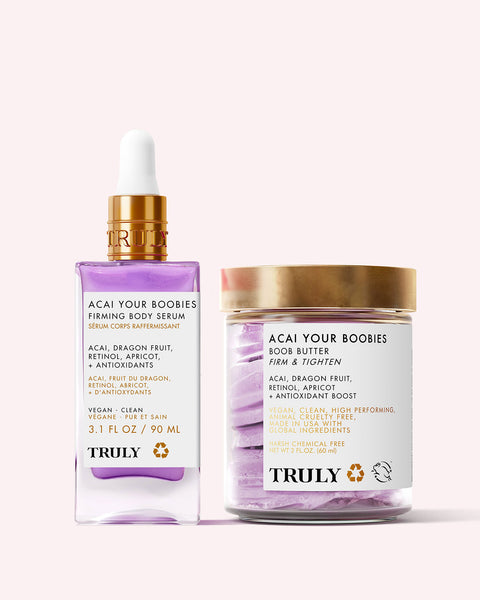 Truly Beauty’s For Your Boobs Routine features a purple-tinted firming serum and a Boob Butter, both in white and gold packaging, designed to firm the chest area. Displayed on a pale pink background.