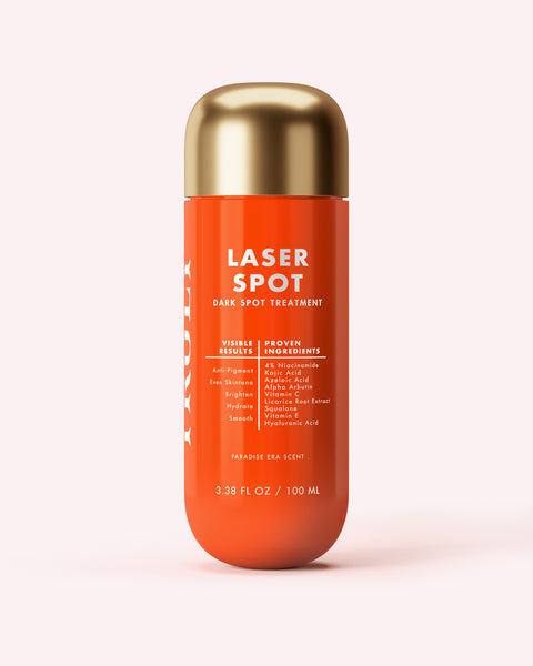 Orange bottle of 'Laser Spot' dark spot treatment with gold cap on a light pink background