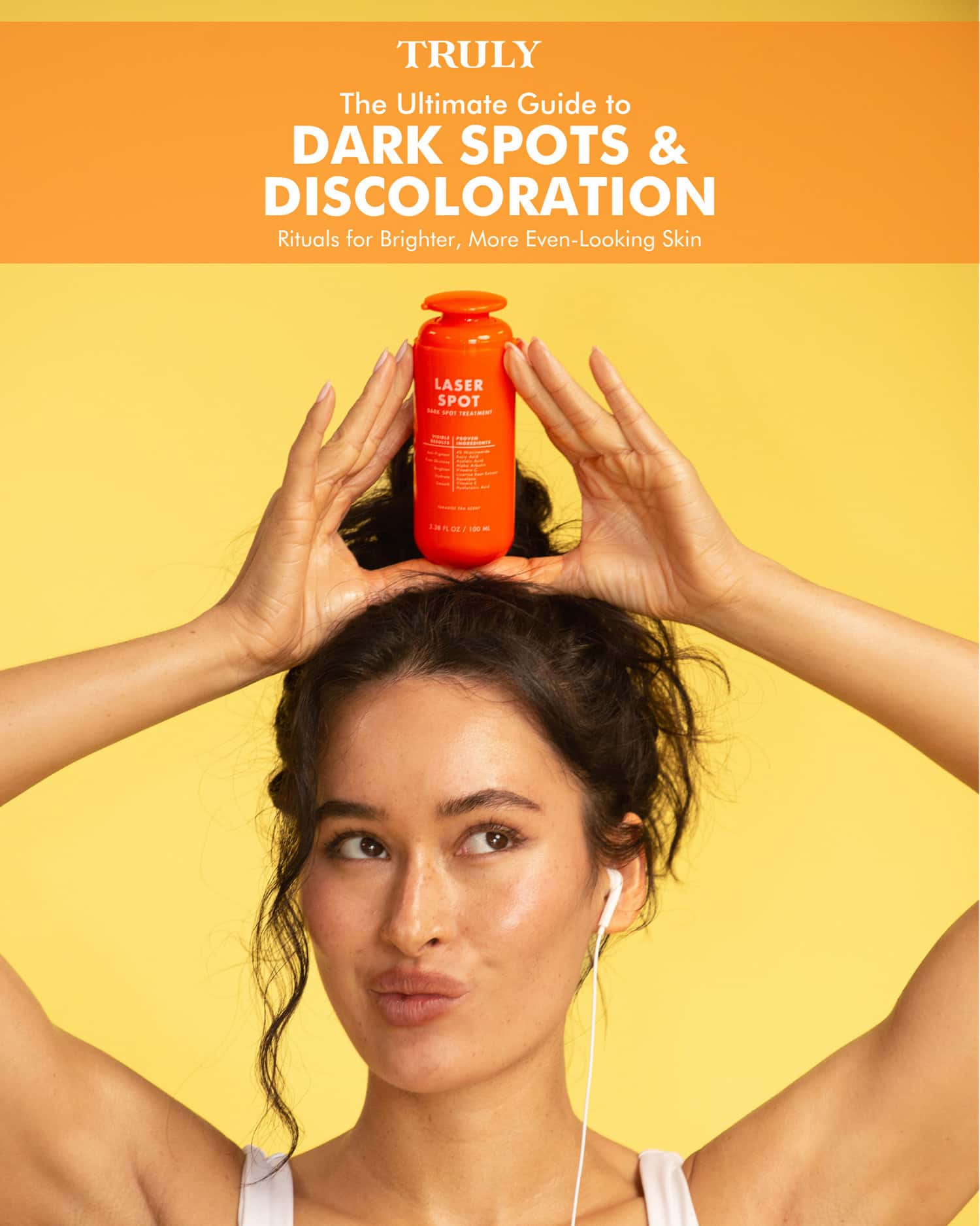 A woman with curly hair holds an orange bottle above her head, puckering her lips. Above her, text reads: The Ultimate Guide to Dark Spots & Discoloration—discover Laser Spot Dark Spot Treatment E-Book by Truly Beauty.