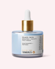 A 3.4 fl oz (100 ml) glass bottle of Truly Beauty’s Glass Skin Brighten + Smooth Face Serum features a gold dropper cap and a label highlighting niacinamide, peptides, and its hydrating formula designed to brighten and smooth the skin.