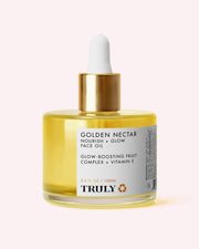 A clear bottle of Truly Beauty Golden Nectar Nourish + Glow Face Oil—an ultra-nourishing facial oil infused with vitamin E—features a white label, gold cap, and dropper filled with yellow oil, shown against a light pink background for instantly glowy skin.